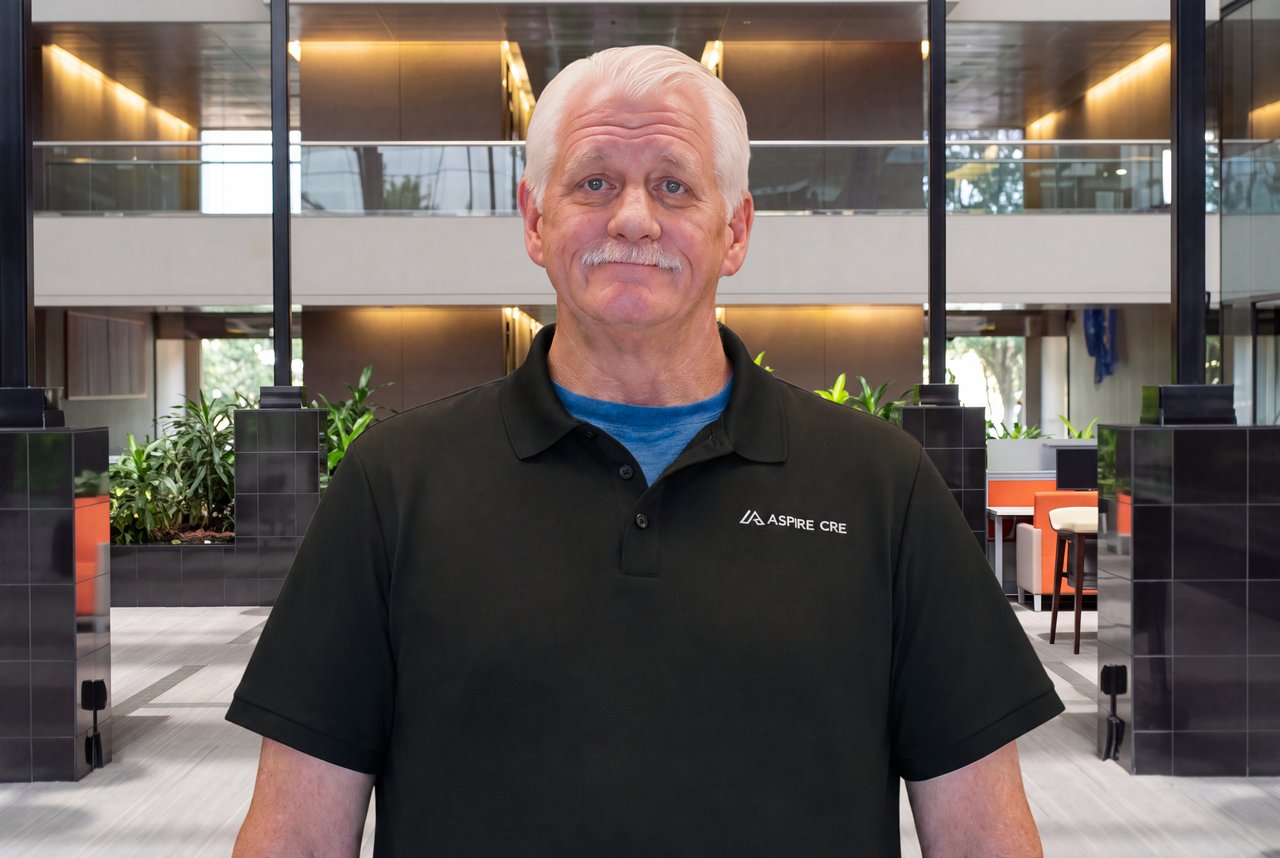 Michael Foster in an Aspire CRE polo in a modern office lobby.