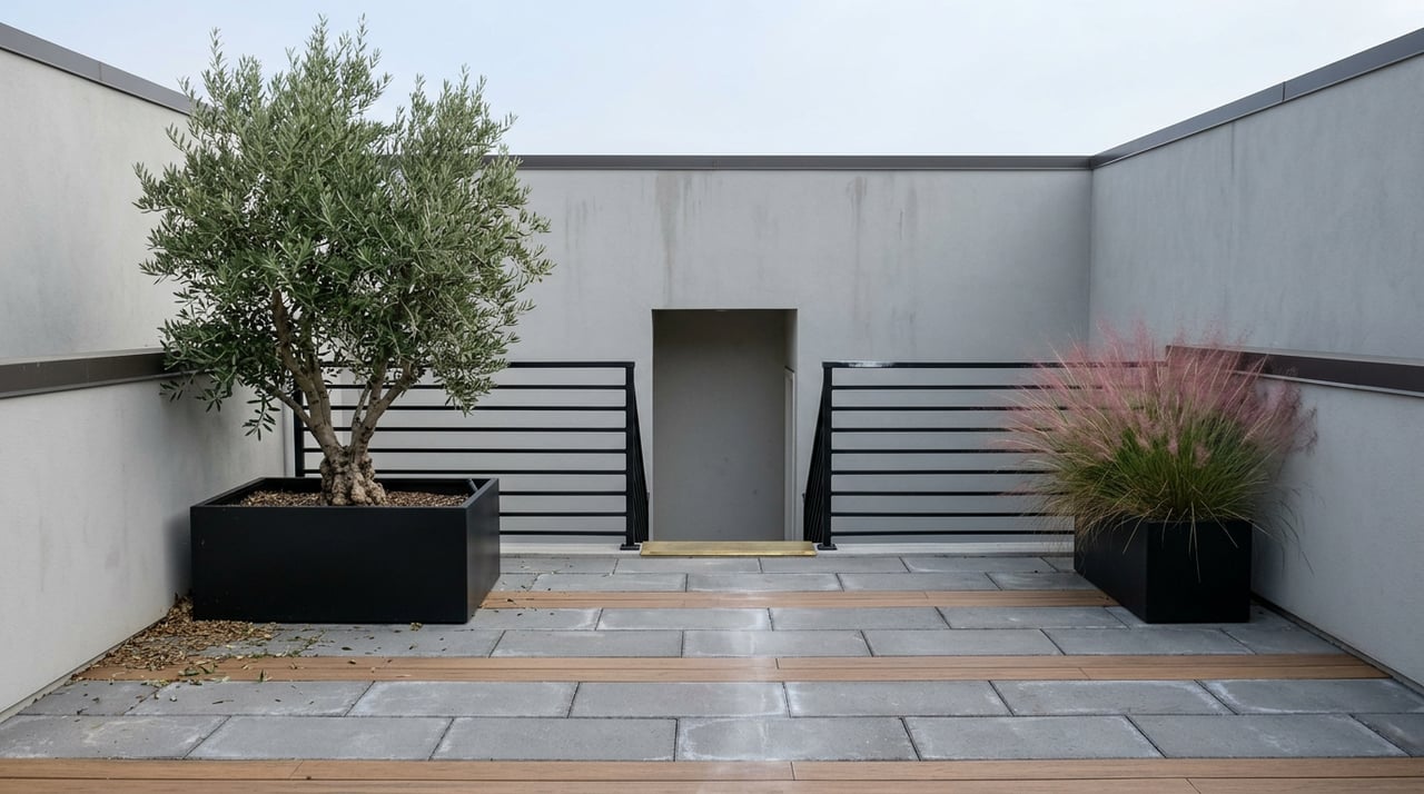 Rooftop terrace with gray pavers, a black guardrail, an olive tree, and pink muhly grass.