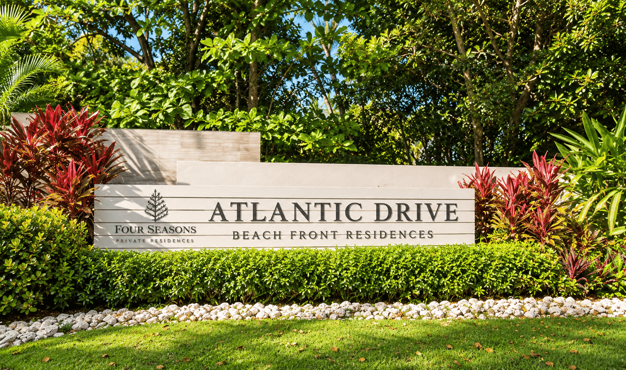 Atlantic Drive Beach Front Residences sign amid tropical landscaping.