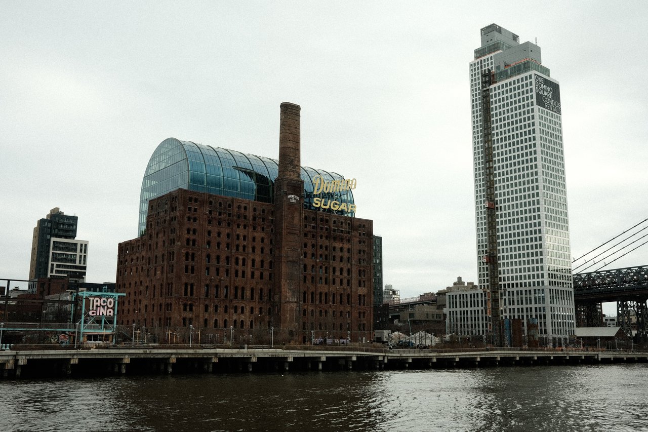 One Domino Square luxury waterfront condominiums in Williamsburg, Brooklyn, featuring architecture by Annabelle Selldorf, panoramic Manhattan skyline views, and resort-style amenities adjacent to Domino Park.