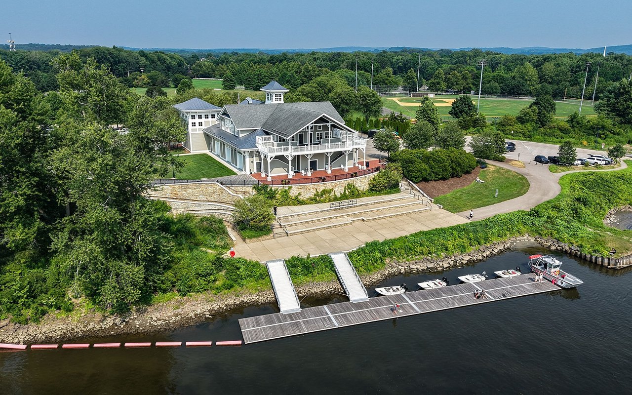 Waterfront complex with a large building, docks, boats, and baseball fields nearby.