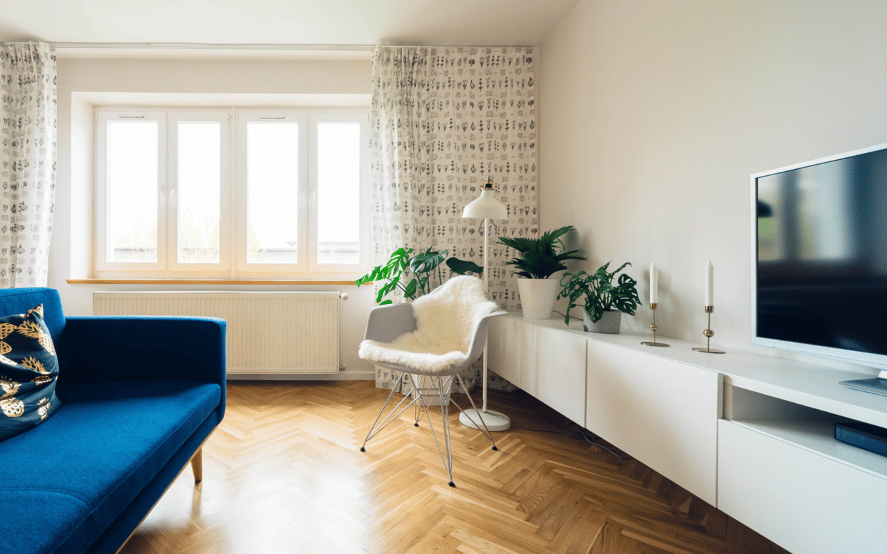  A cozy living room featuring a long, bright blue sofa on the left with a patterned gold and black throw pillow.