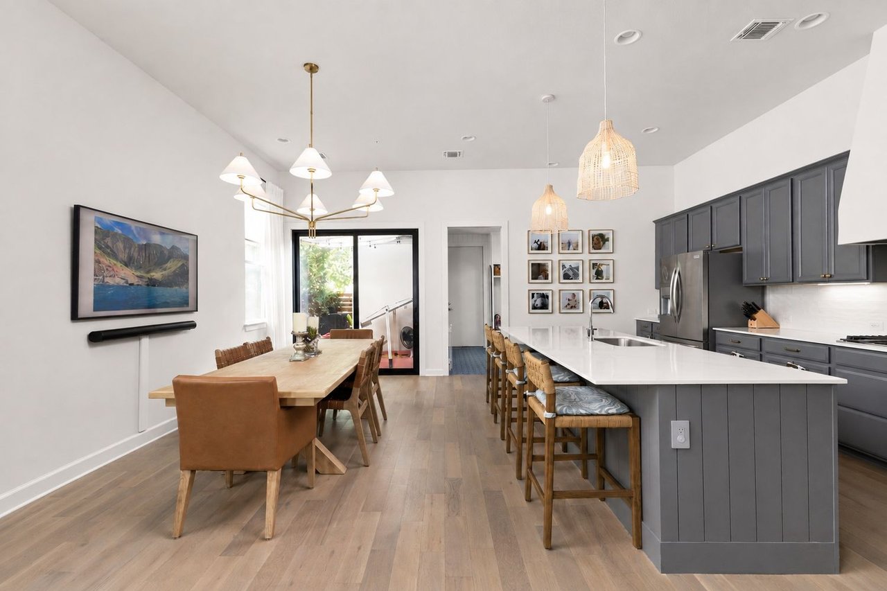 Open-plan kitchen and dining area with a large island, gray cabinets, and sliding glass doors.