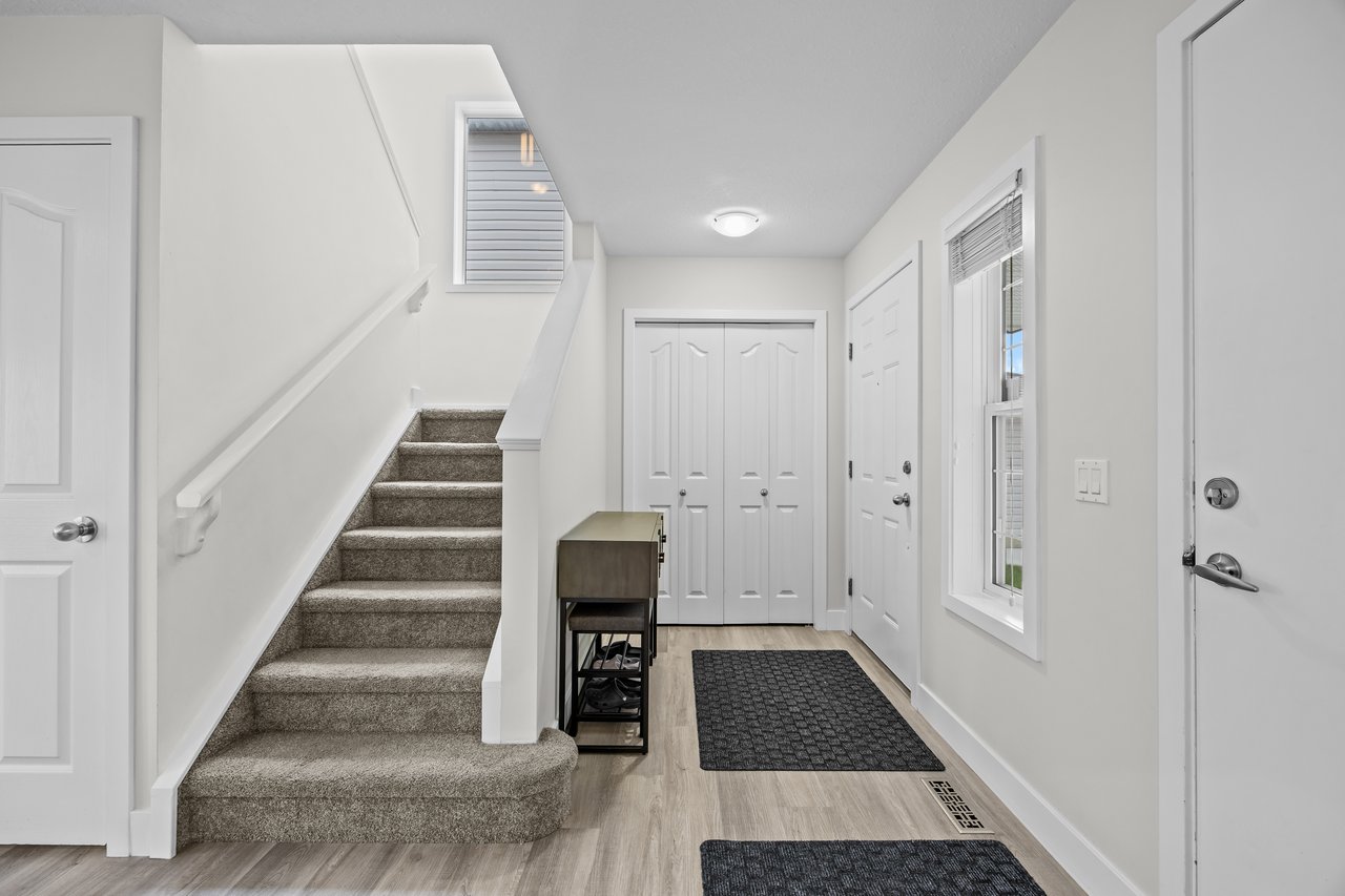 Entryway with carpeted stairs, double closet doors, and a small console table.