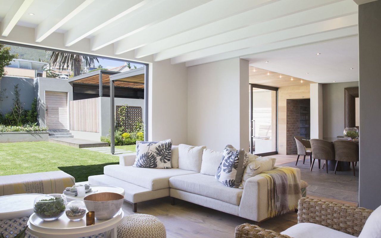 Bright living room with a white sectional and glass doors opening to a landscaped lawn.