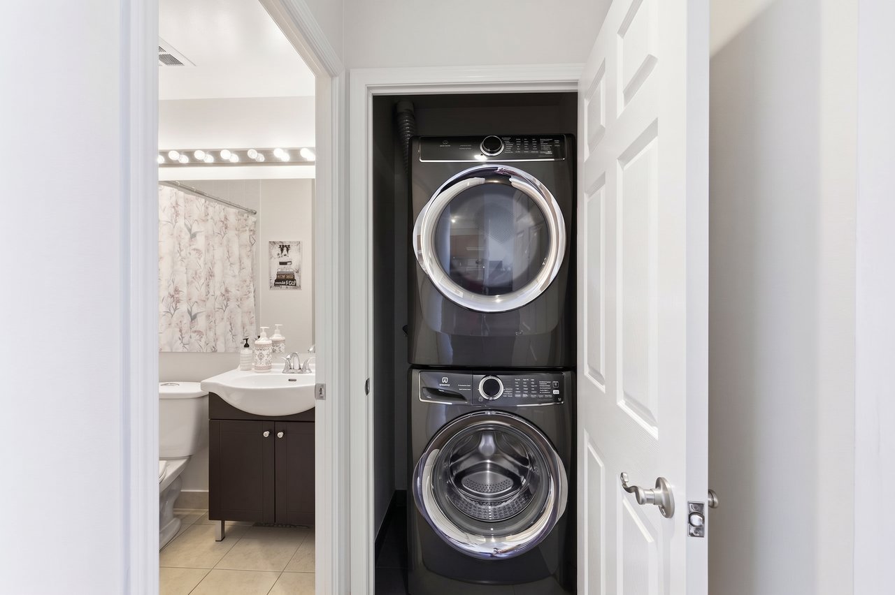 Stacked washer and dryer in a closet beside a bathroom vanity.