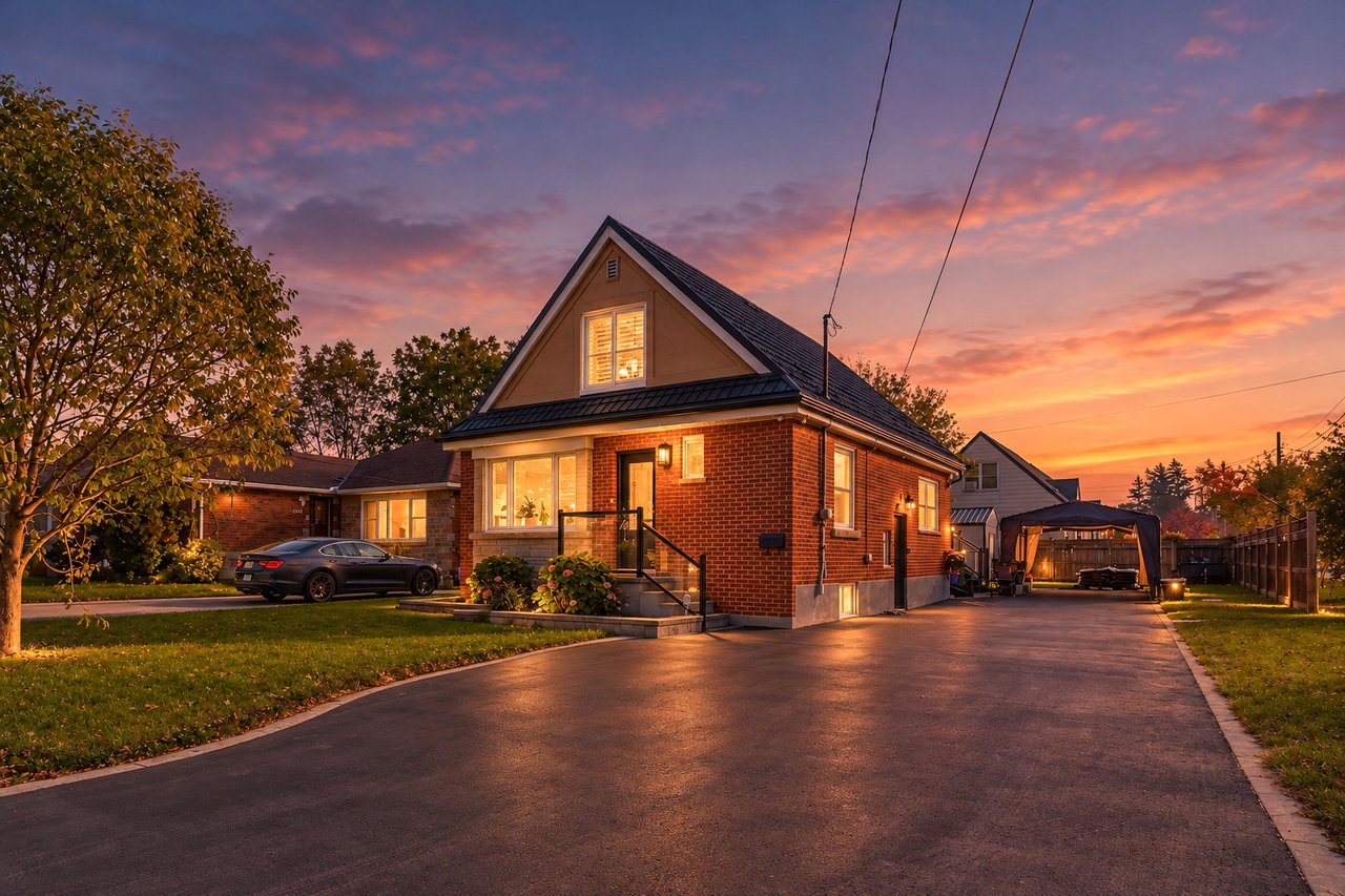 Red-brick house with a steep gabled roof and broad driveway glowing at dusk.