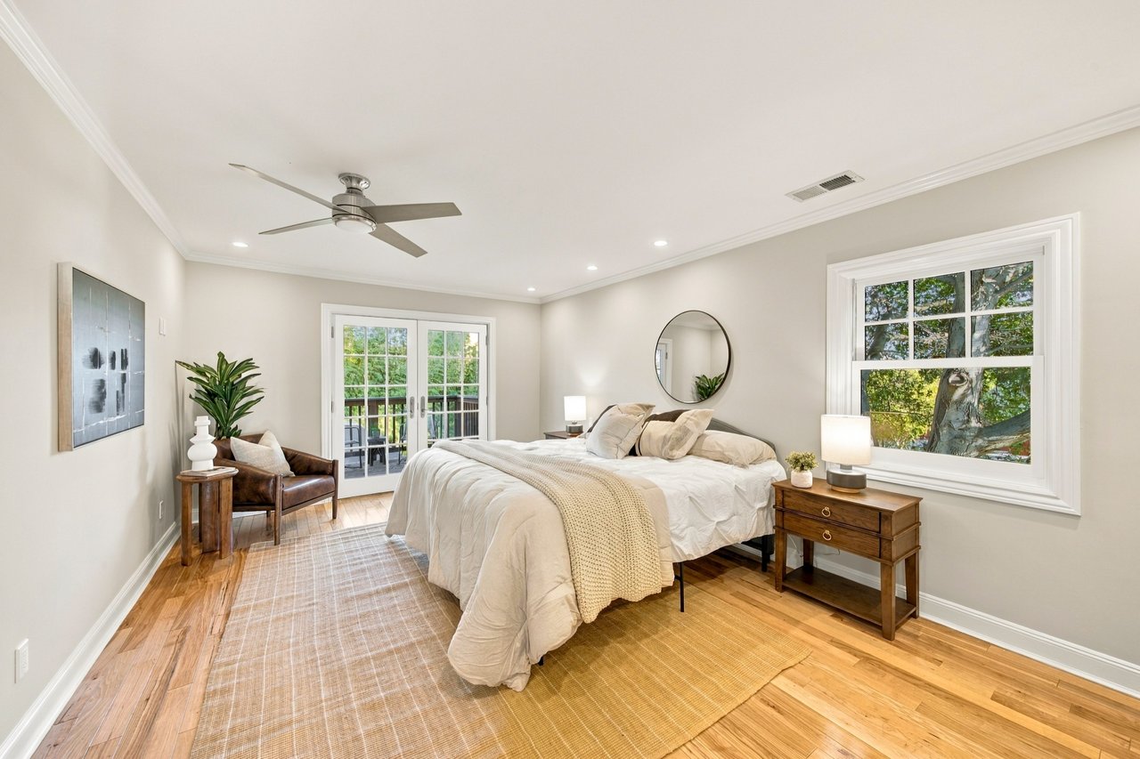 Bright bedroom with a large bed, hardwood floors, and French doors opening to a balcony.