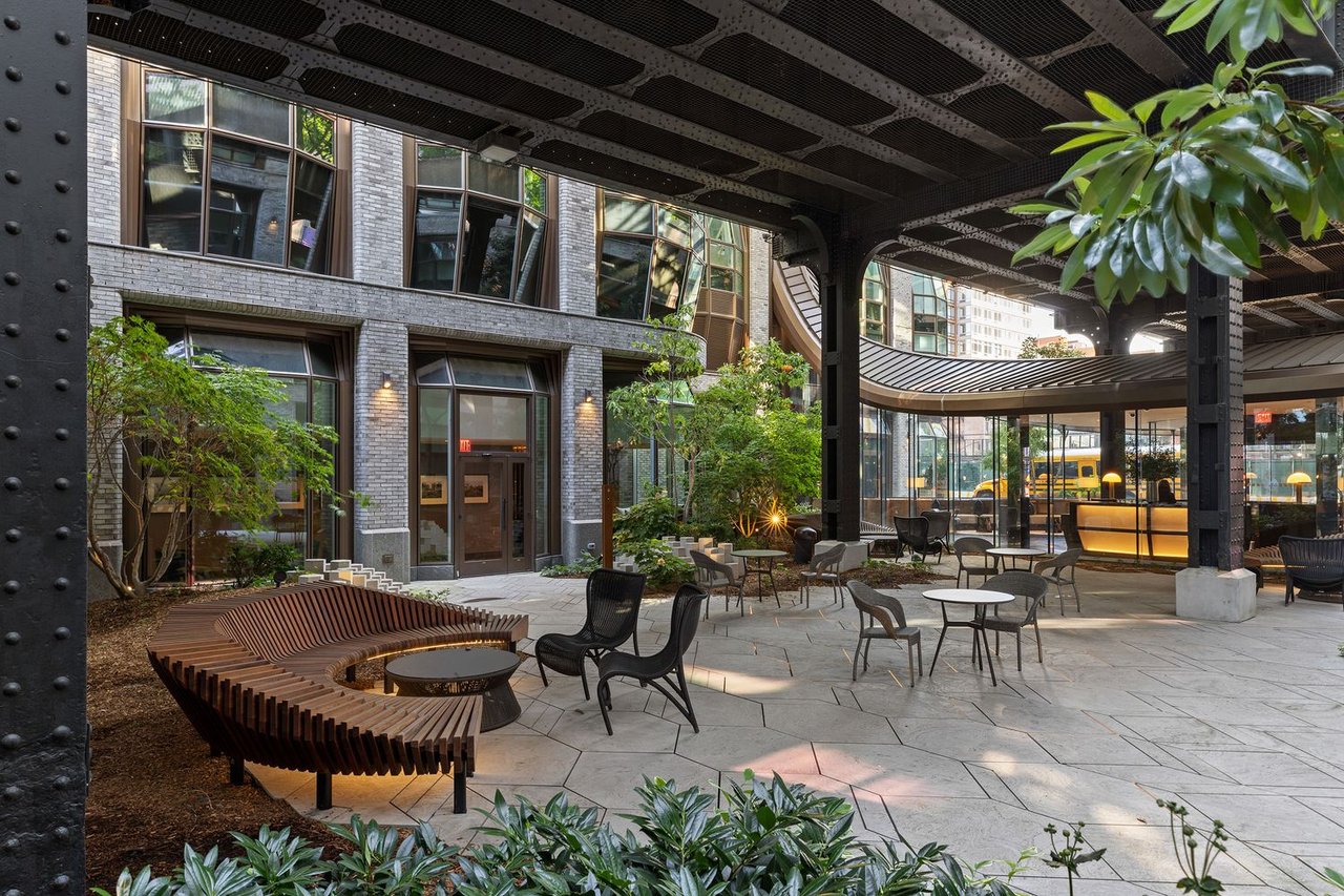 Lantern House courtyard with a curved wooden bench, outdoor seating, and a steel canopy.