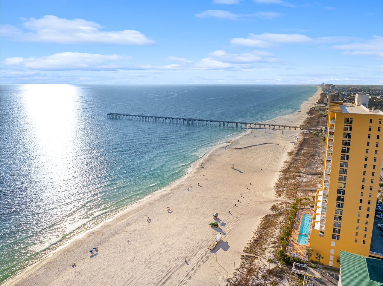 ial view of a fishing pier over the sunlit Gulf in Panama City Beach