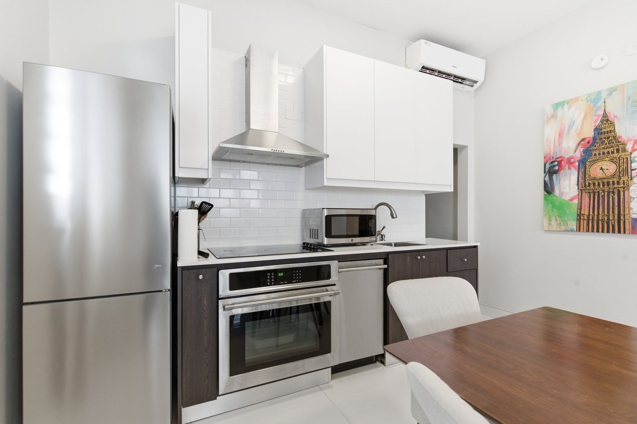 Modern kitchen with stainless steel appliances, white subway tile, and a dining table.