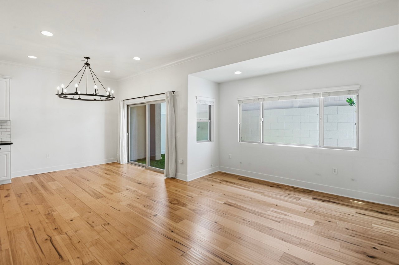 Living area with iron ring chandelier, sliding glass patio doors, transom windows, and natural light on hardwood floors