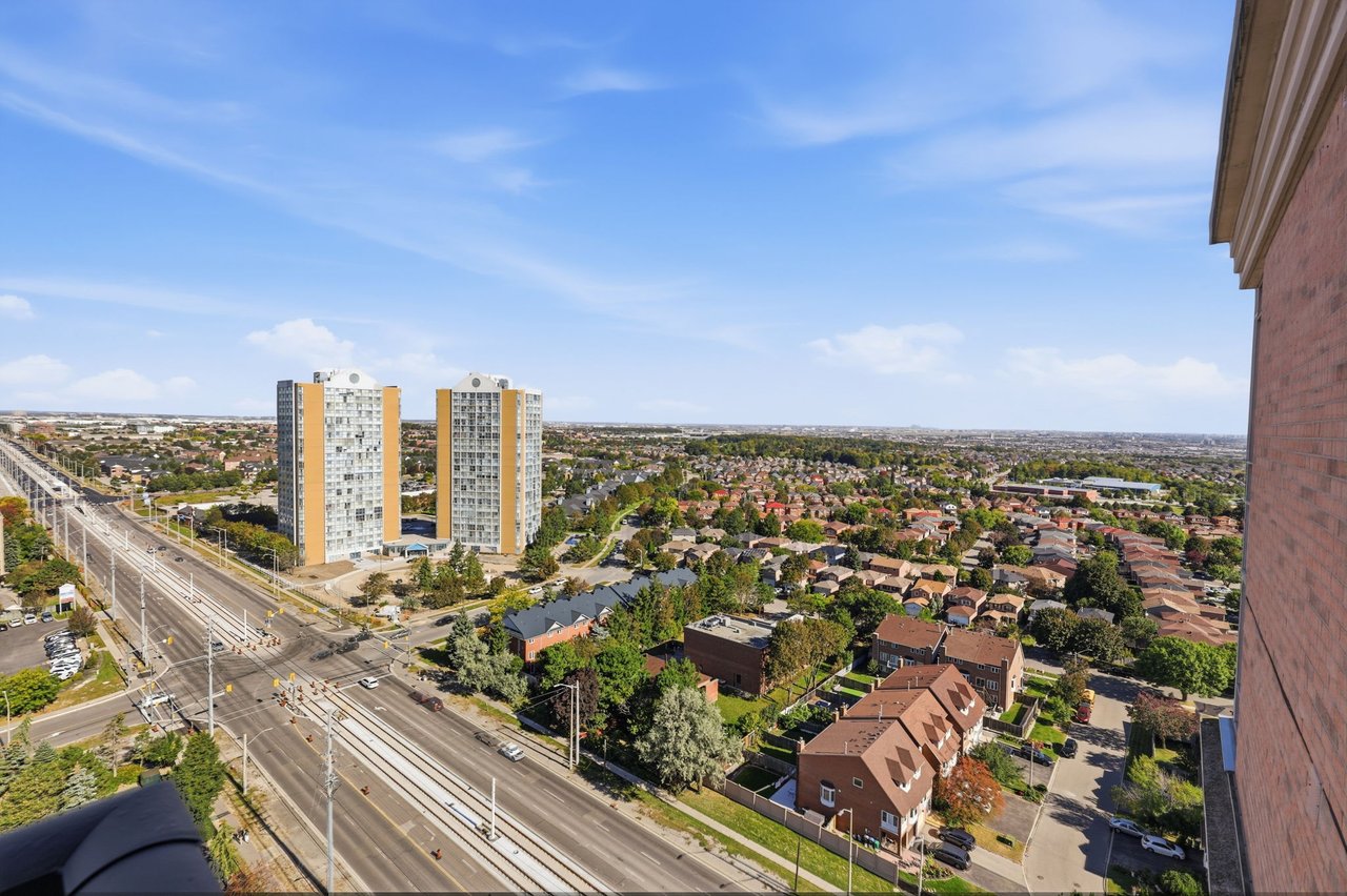 Panoramic Mississauga view with two nearby towers, residential neighborhoods, and a transit corridor.