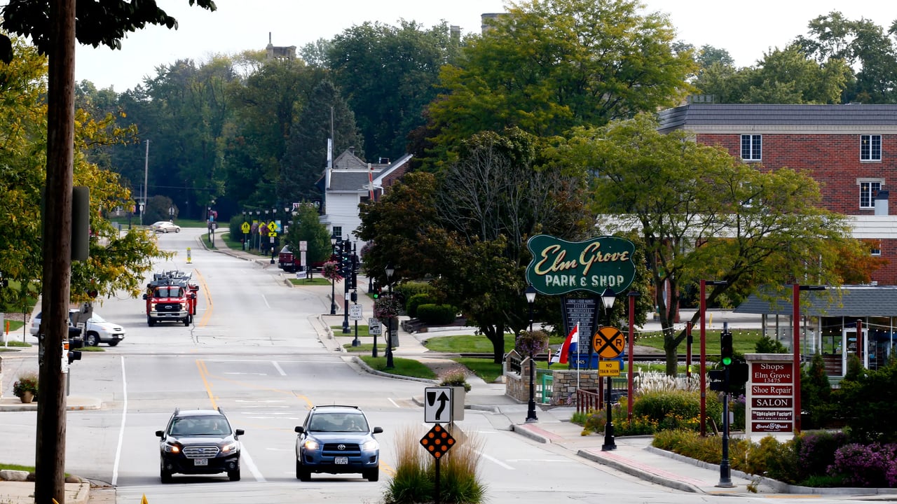 Downtown Elm Grove with cars on Watertown Plank Road and the Elm Grove Park and Shop sign along the street