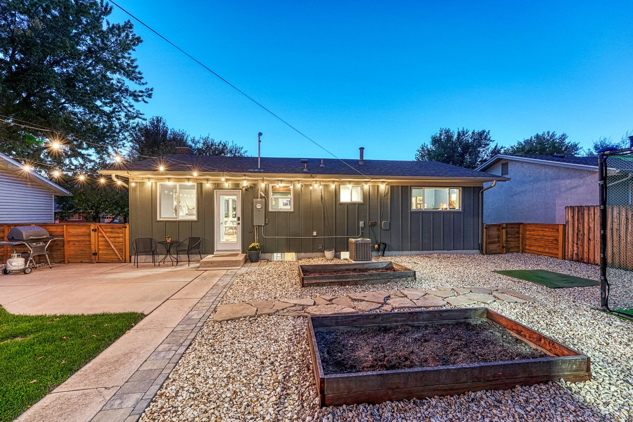 Raised garden beds and a flagstone path behind the house at dusk