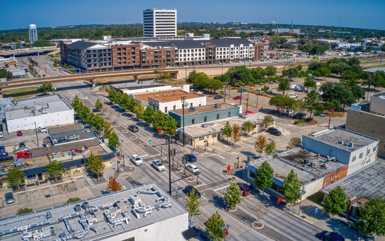 Aerial view of Richardson’s commercial district, with rail tracks, tree-lined streets, and an office tower.