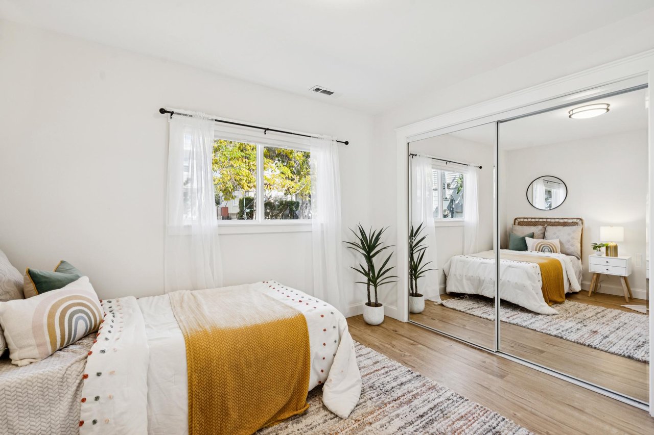 Staged bedroom with a mustard-yellow bed throw and mirrored sliding closet doors.