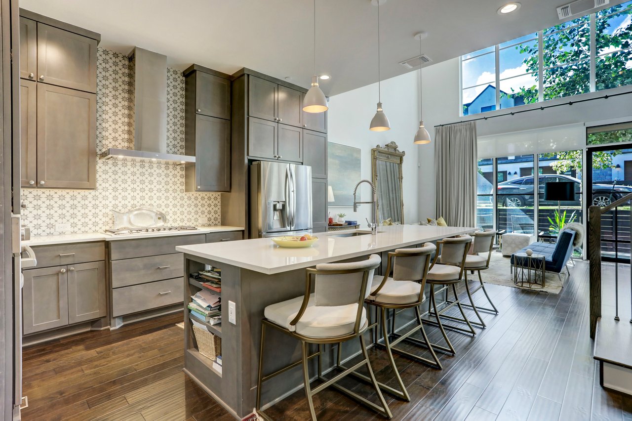 Kitchen at The Grove townhome on Unity Circle, Austin, TX, with a center island, seating for four, patterned tile backsplash, and stainless steel appliances.