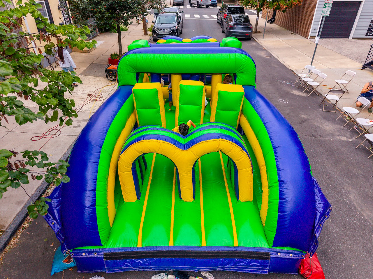 Children play on a bright inflatable obstacle course set up on a neighborhood street.