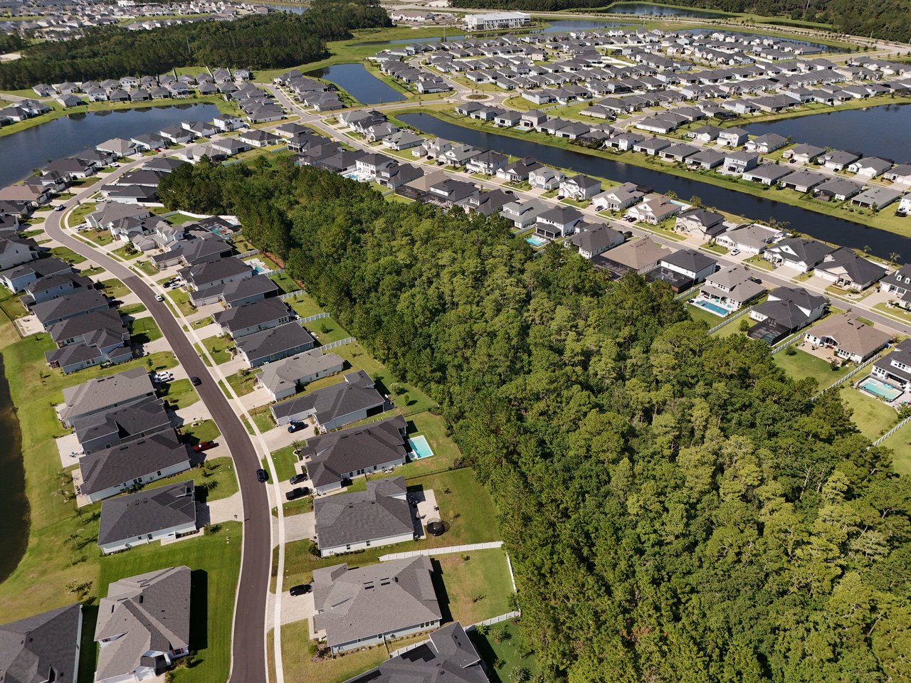Aerial view of Silver Landing homes beside waterways and a wooded greenbelt.