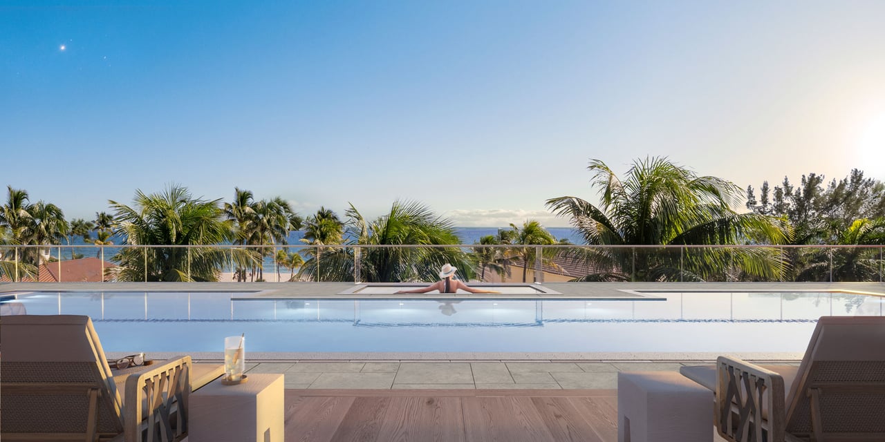 Rooftop pool and terrace overlooking palm trees and the ocean.