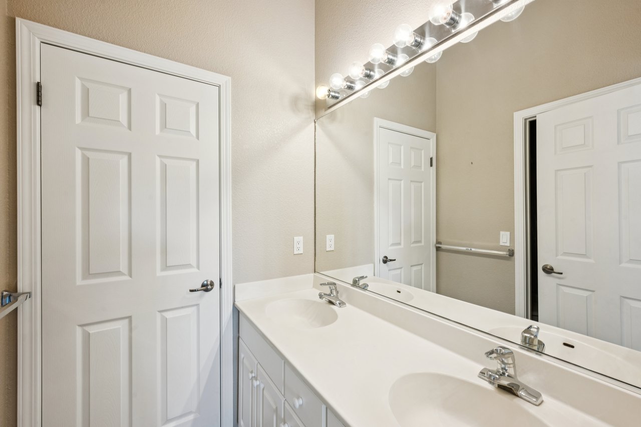 Bathroom vanity with two sinks, chrome faucets, and a large mirror.