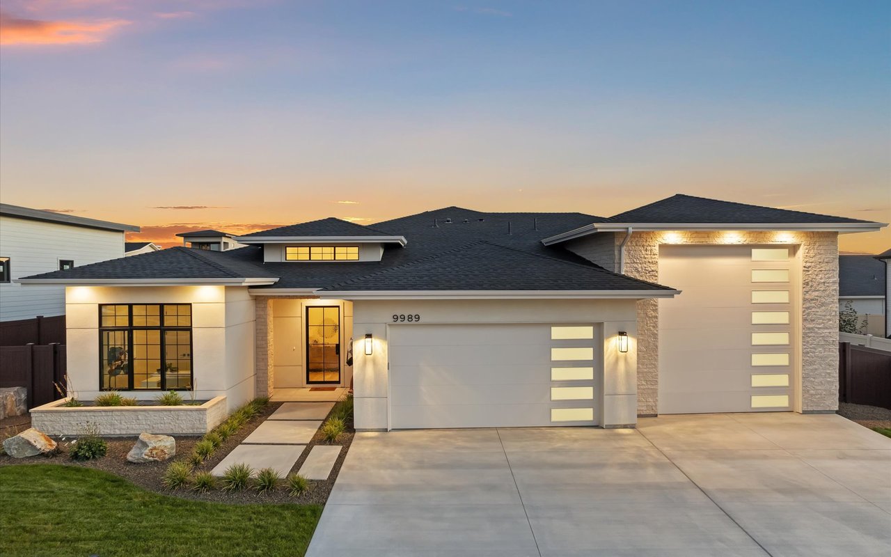 Extensively landscaped modern prairie new construction home with stucco and stone, black steel front door, and RV garage.