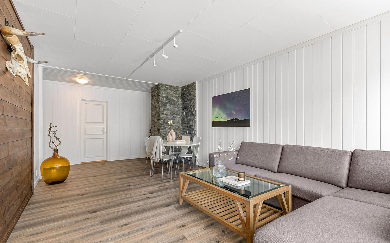 Living room with gray seating, a glass-top coffee table, and an adjoining dining area.