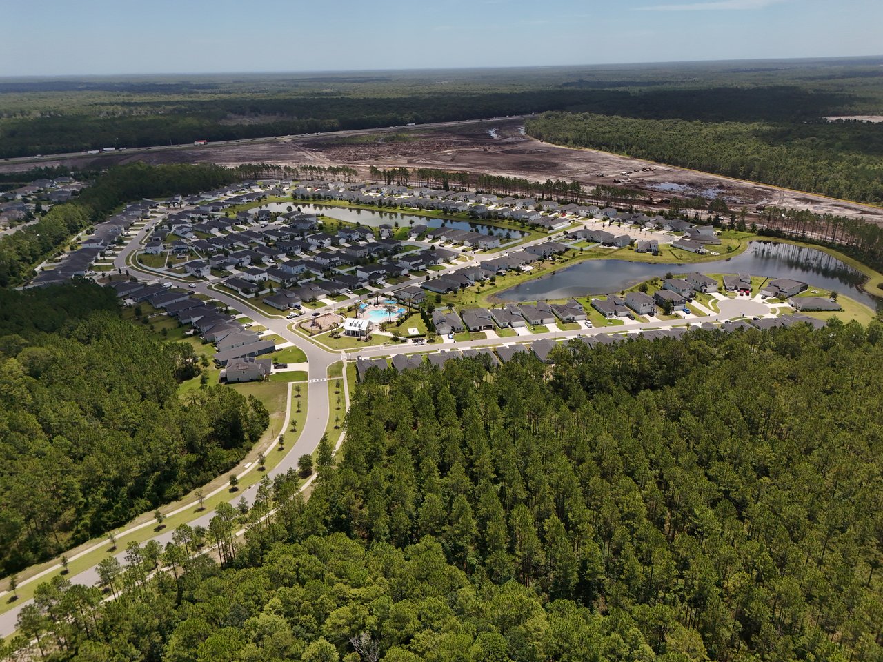 Aerial view of Meadow Ridge homes, community pool, ponds, and surrounding woodland.