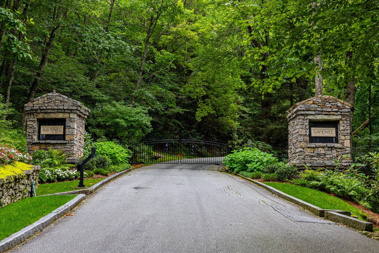 Stone pillars with RAVENEL signs and an iron gate at the wooded entrance to Ravenel in Highlands, NC