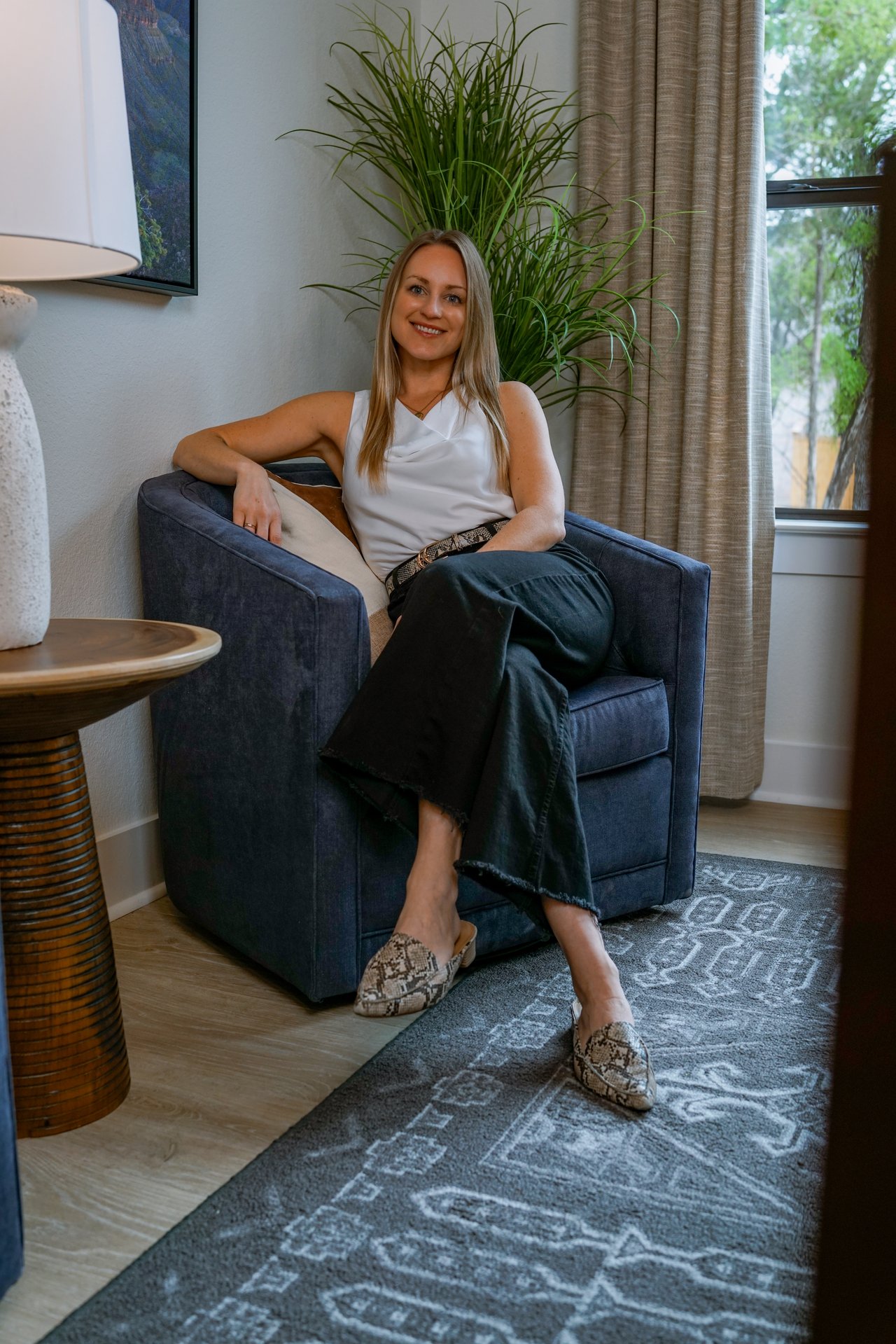 Elizabeth Ross seated in a navy armchair, smiling in a bright living room.