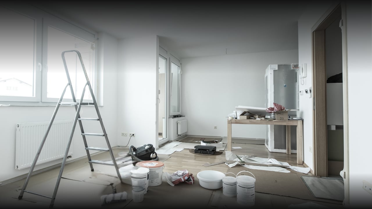 Unfinished room under renovation with a step ladder, paint buckets, and tools on the floor.