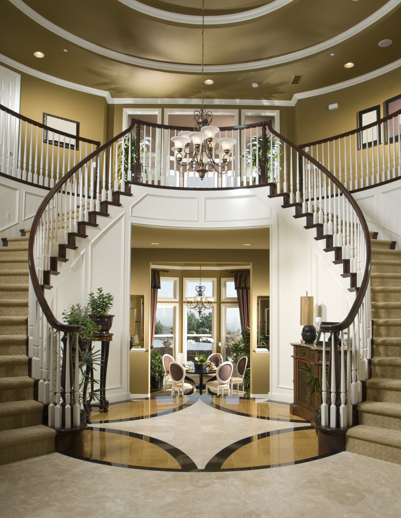 Foyer with a sweeping double staircase, chandelier, and patterned marble floor.