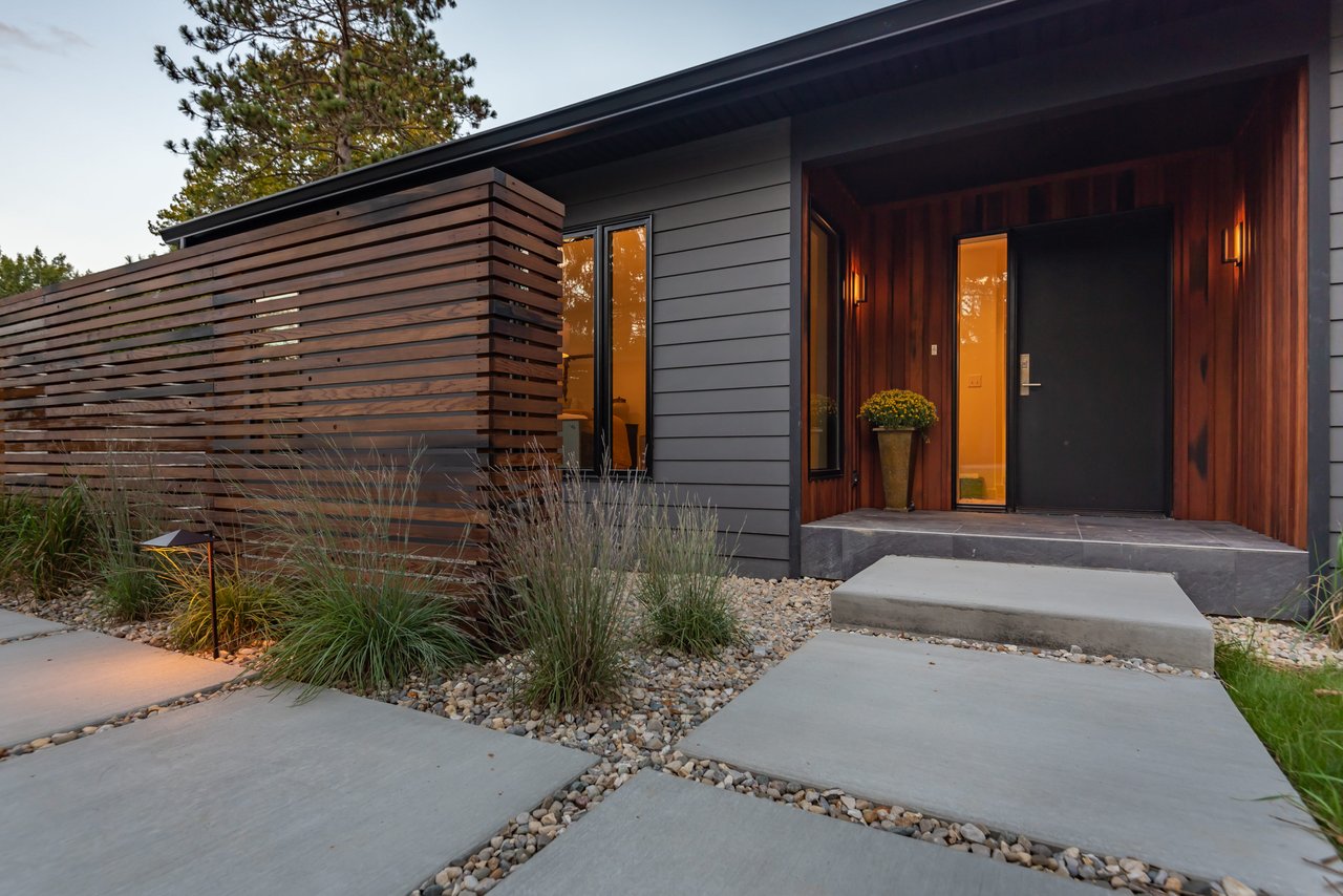 Modern home entrance with a wood-slat screen and warmly lit recessed doorway.