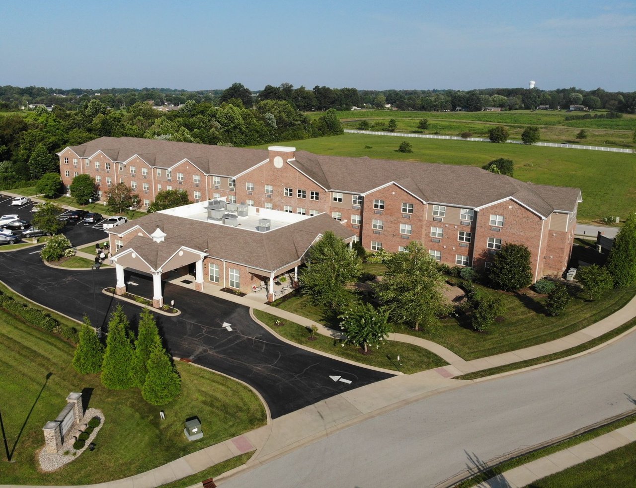 Aerial view of a red-brick senior living community with a covered entrance and landscaped grounds.