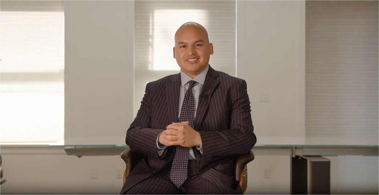 Flavio Avila seated in a pinstripe suit in a bright office.