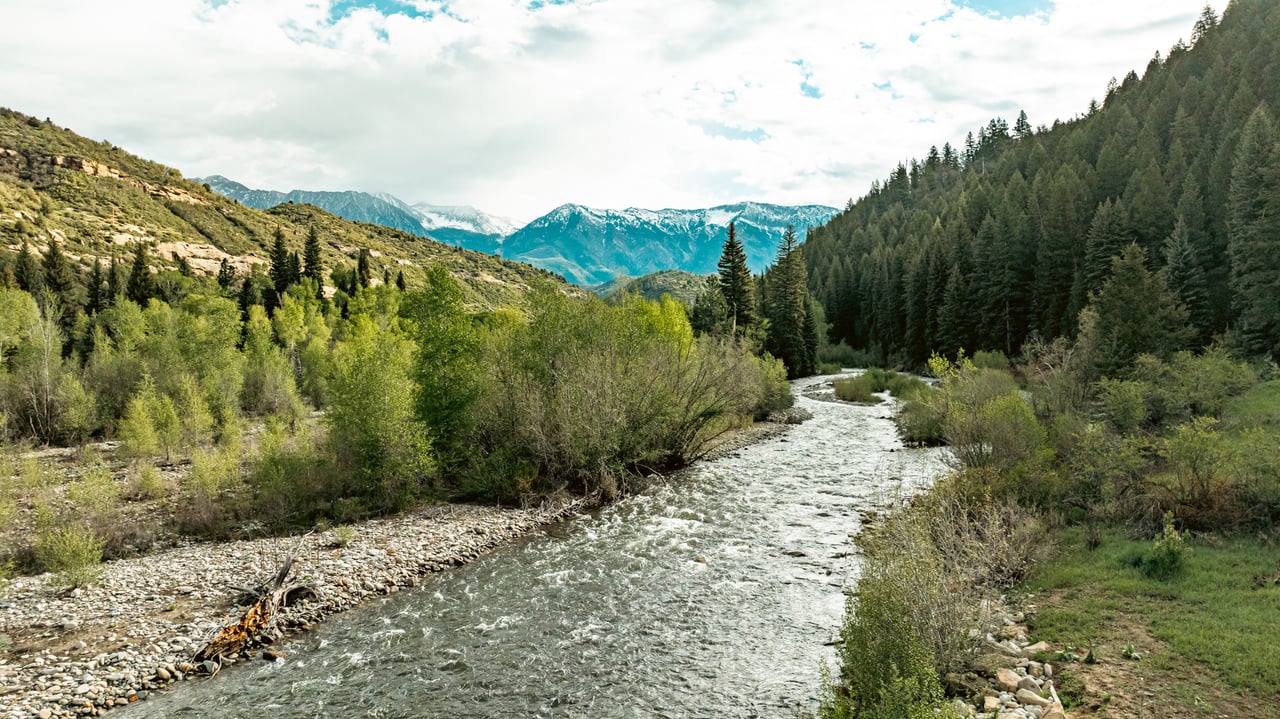 River winding through a mountain valley with rocky banks and snow-dusted peaks.