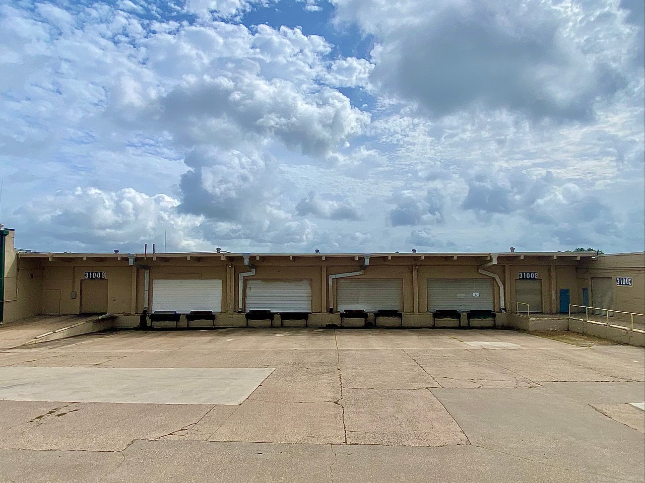 Commercial warehouse loading docks with multiple roll-up doors and a wide concrete apron.