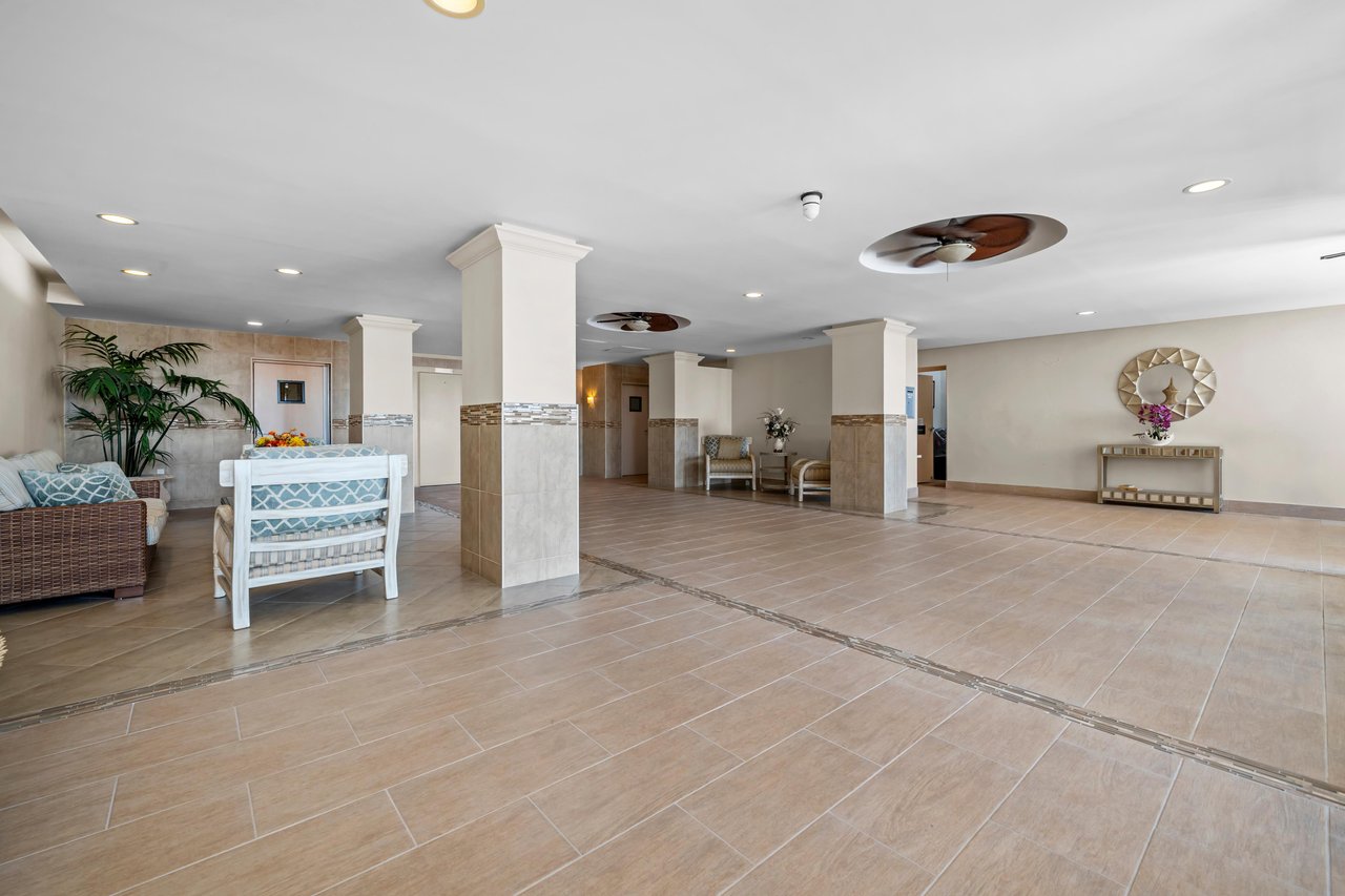 Building lobby with tiled floors, square columns, ceiling fans, and seating.