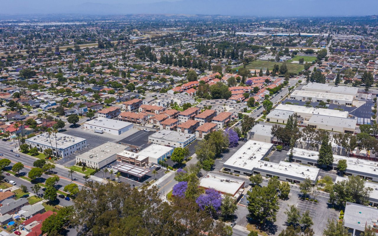 Aerial view of Santa Fe Springs with homes, commercial buildings, and distant mountains.