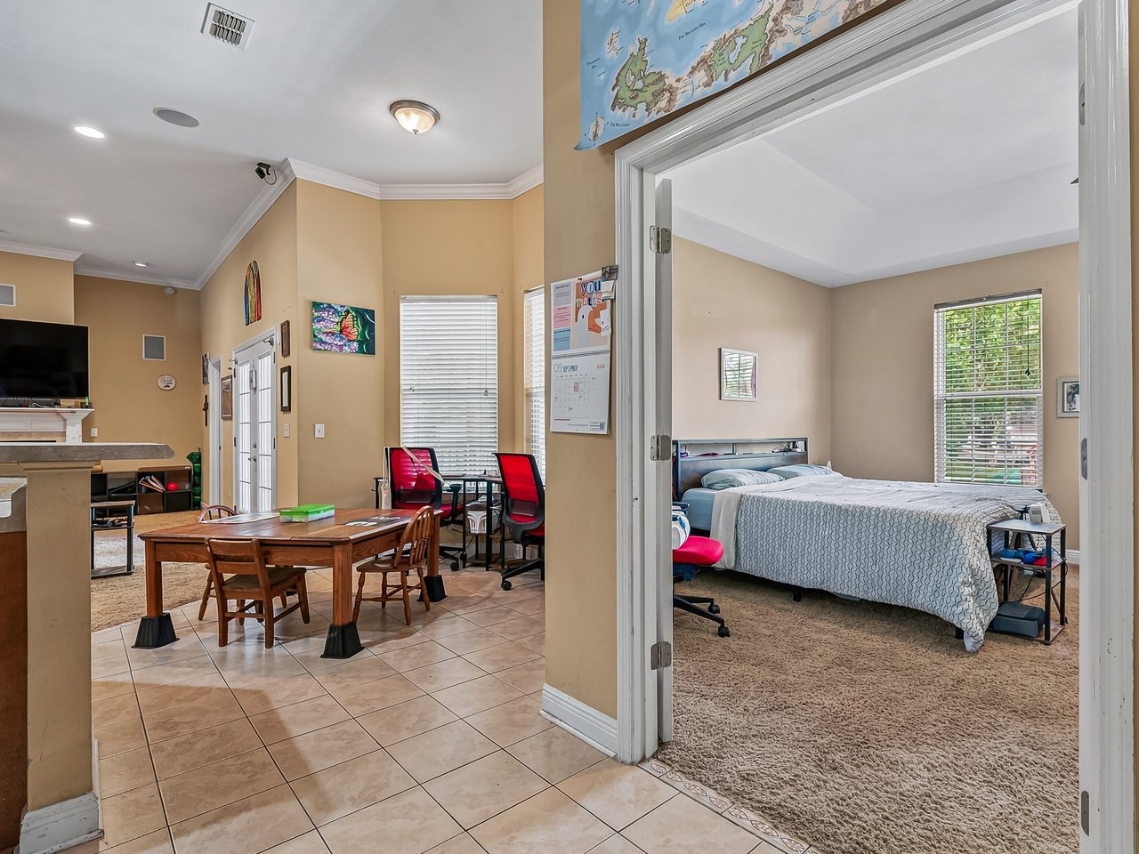 Dining area with a wooden table and red chairs beside a carpeted bedroom.