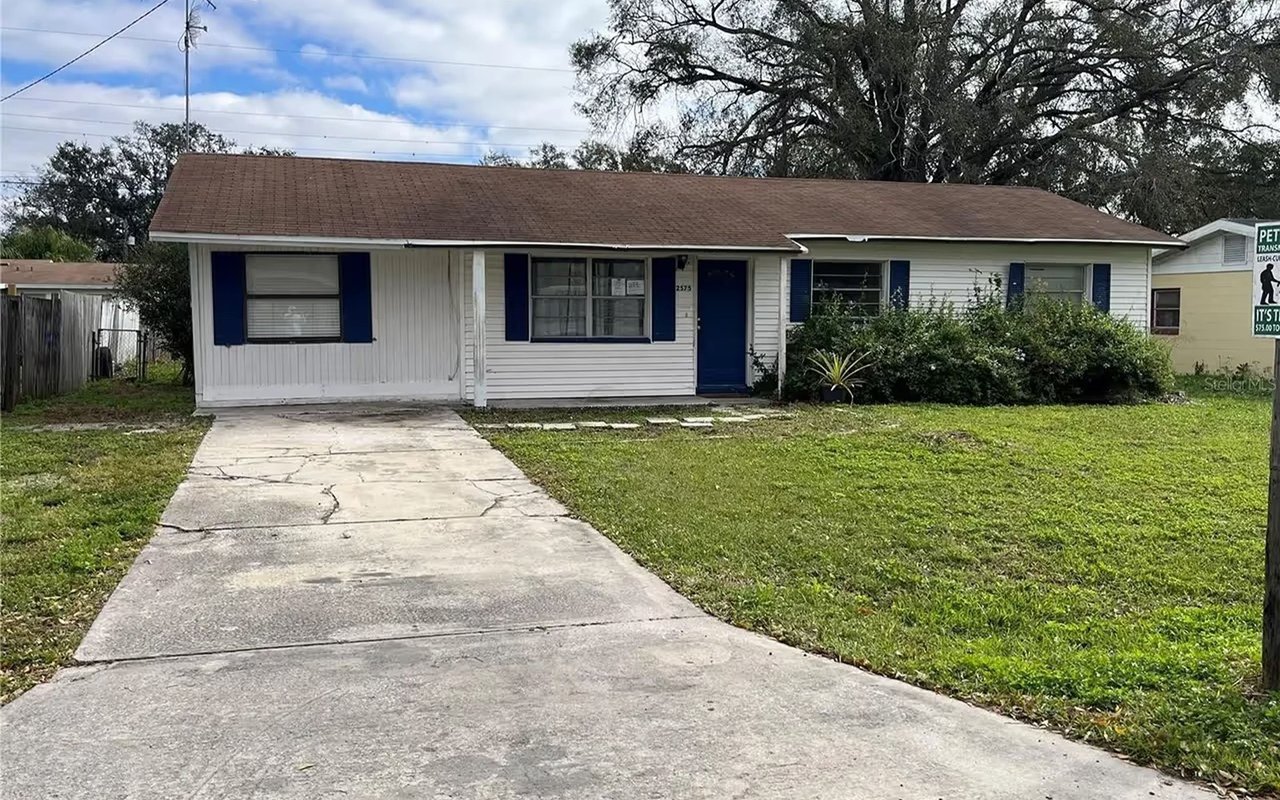 White single-story house with navy shutters and door, a concrete driveway, and a grassy front lawn.