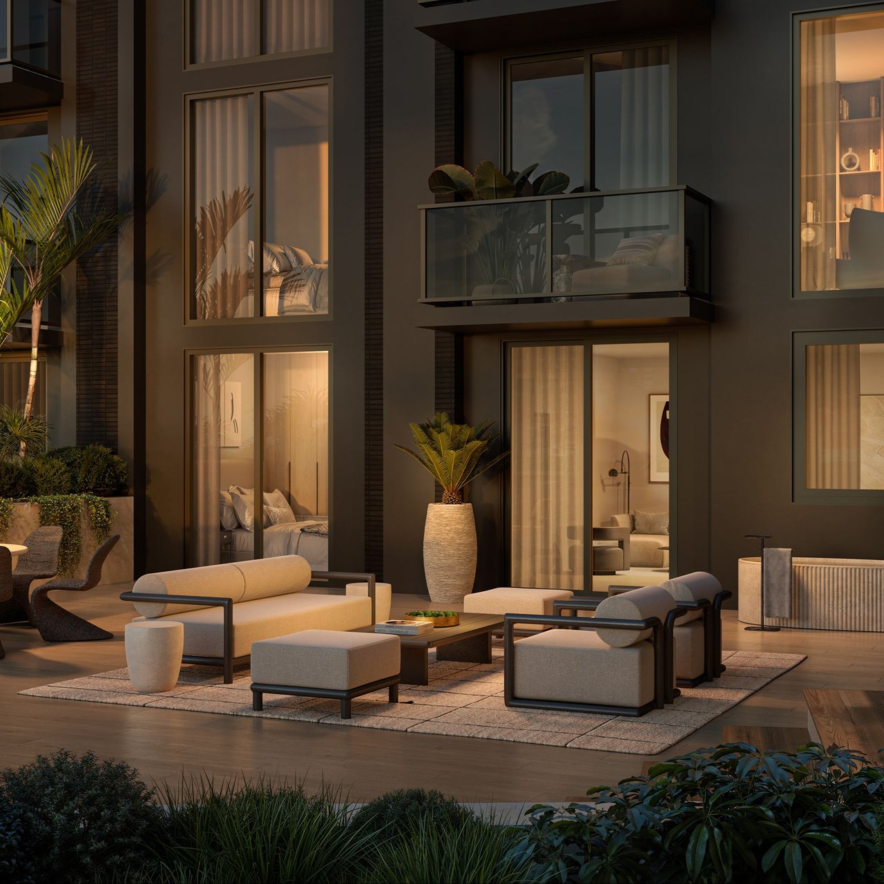 Furnished terrace beside a modern residence, with glass balcony and lounge seating at dusk.