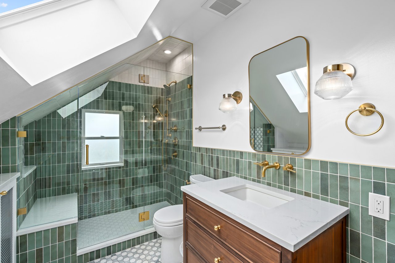 Modern, renovated green tile bathroom with gold hardware and skylight - STS Construction Services in West Seattle