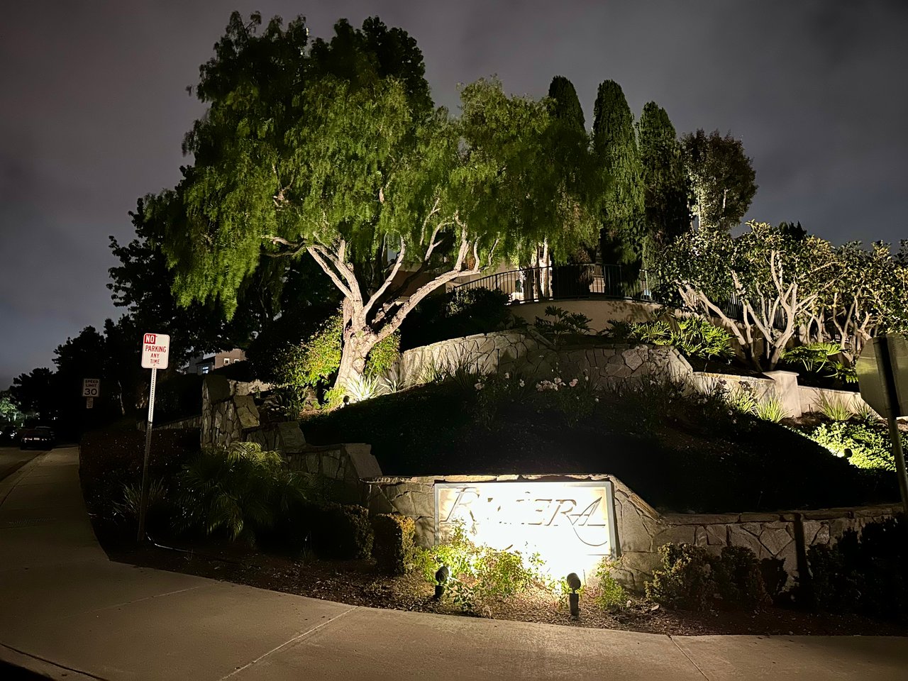Riviera entry monument in Bear Brand, Laguna Niguel — illuminated stone signage and stone wall framed by mature trees