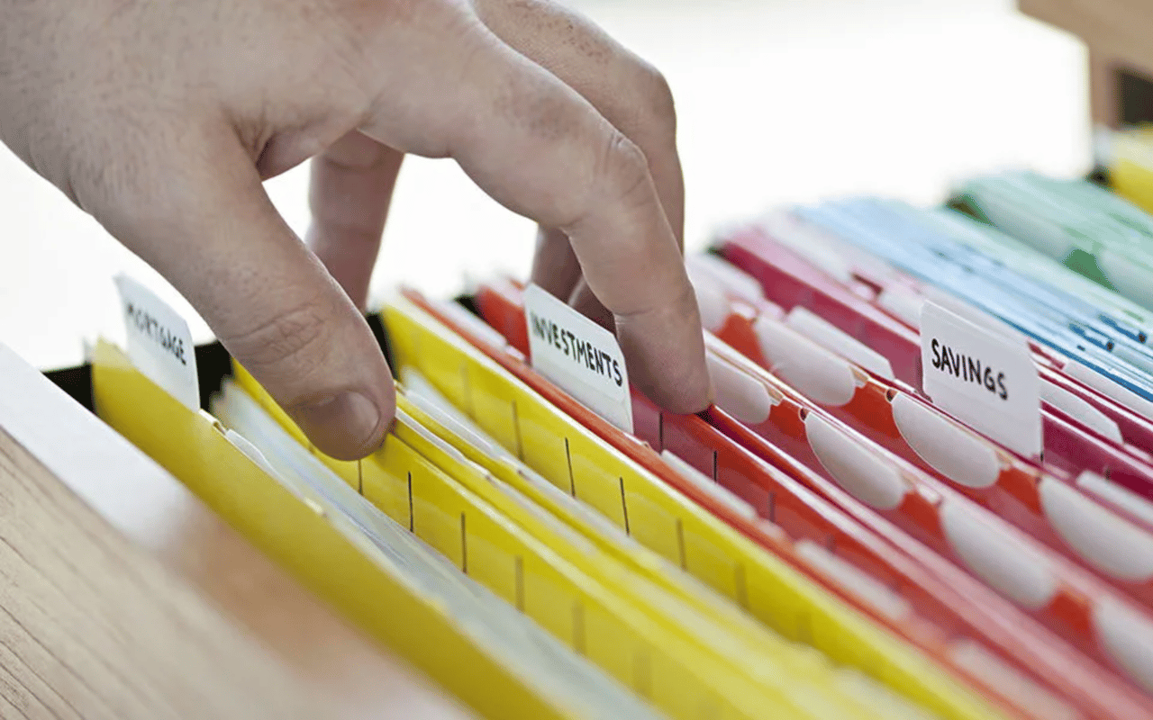 A hand sorts financial folders labeled Investments and Savings.