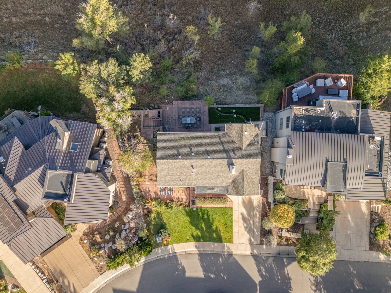 Overhead drone view of the 2003 Balsam Drive lot showing the home, front lawn, and wooded slope toward Goose Creek