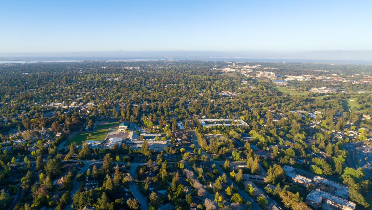Aerial view of Menlo Park’s tree-filled neighborhoods, school fields, and distant bay.