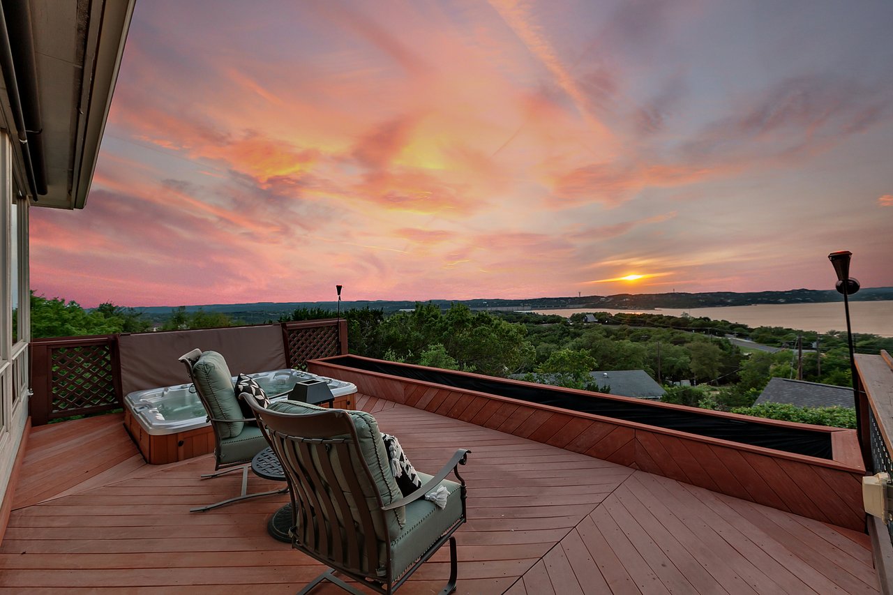 Twilight view of the covered deck with hot tub and panoramic Lake Travis and Hill Country views at 12709 Cedar St, Austin, TX 78732, in the Hughes Park Lake neighborhood.