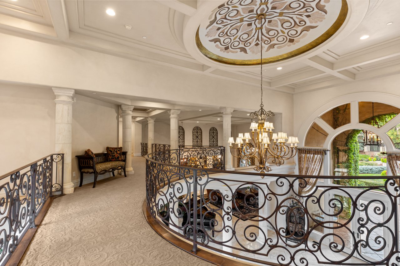 Grand two-story foyer with an ornate ceiling medallion, chandelier, and wrought-iron balcony railings.